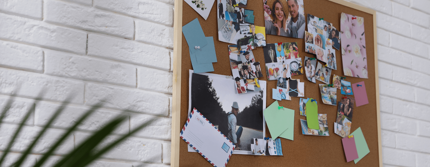 A corkboard decorated with photos, notes, and memories, creating a gratitude wall on a white brick background.