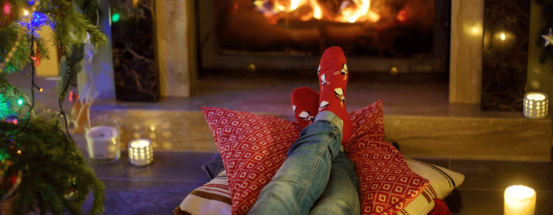 Cozy scene with someone relaxing by a fireplace, wearing festive socks.