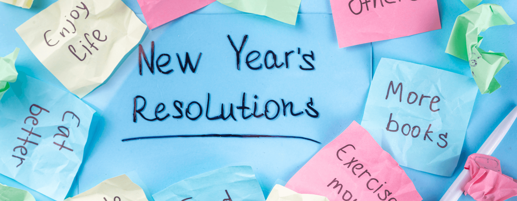 Handwritten New Year's resolutions on colorful sticky notes surrounding a blue background.